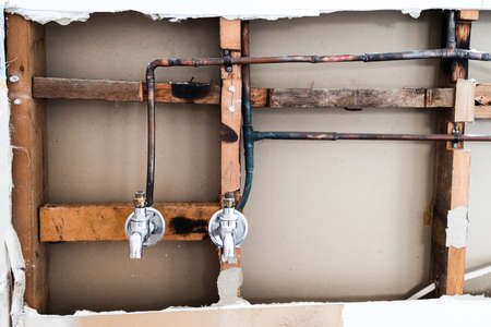 laundry room renovation with plaser walls interior exposed with taps and copper pipes, concept of...
