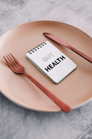 gut health text on notepads on top of dining plate with fork and knife, concept of healthy nutrition...