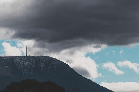 snow on mountain tops in Tasmania, Australia surrounded by beautiful contrasty clouds shot with telephoto lensの写真素材
