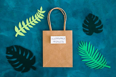 environmental awareness and consumer behaviour conceptual image, Sustainable Product text on shopping bag with tropical green paper leaves on itの写真素材