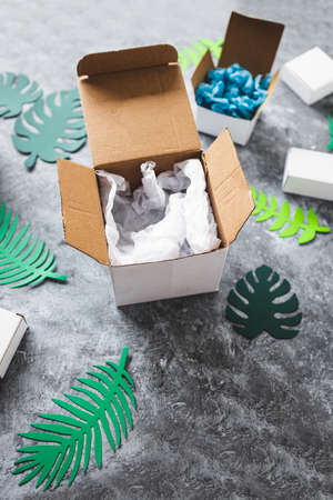 online delivery parcel boxes with different shapes surrounded by green paper leaves, concept of...