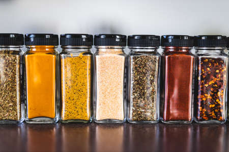 spices seeds and seasonings in matching spice jars on tidy pantry shelf, simple vegan ingredients and concept of flavoring your dishesの写真素材