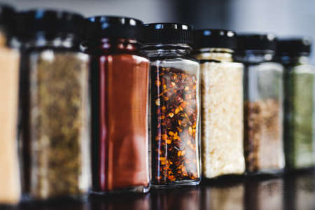 spices seeds and seasonings in matching spice jars on tidy pantry shelf, simple vegan ingredients and concept of flavoring your dishesの写真素材