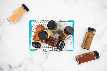 spices and seasonings in matching spice jars in ngrocery shopping basket, concept of simple vegan ingredients and flavoring your dishesの写真素材