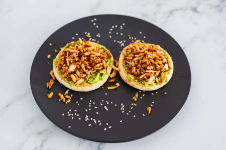 vegan shredded marinated teriyaki tofu with avocado guacamole on top of English muffins, healthy...