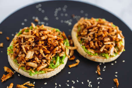 vegan shredded marinated teriyaki tofu with avocado guacamole on top of English muffins, healthy...