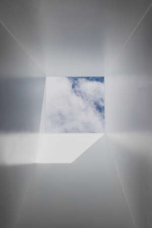 skylight or roof window with view of blue serene sky above and brand new plastered walls, concept of home improvements and architectural features in a propertyの写真素材