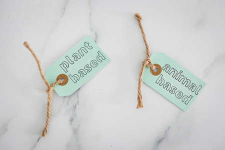 plant-based and animal-based labels on top of marble table, concept of healthy nutrition and ethical...