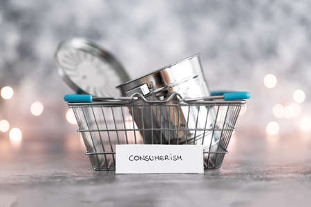 consumerism conceptual image, shopping basket symbol of good to be purchased with recycling bin symbol of excess goods being produced or bought with labelsの写真素材