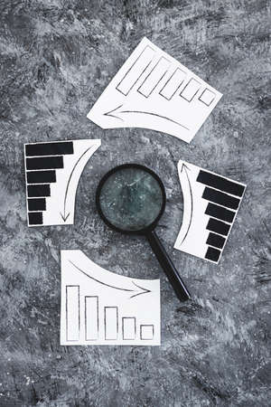 financial markets or money and investments conceptual image, magnifying glass with charts showing...