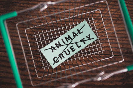 Crossed out animal cruelty product label with grocery shopping basket, concept of healthy nutrition and ethical choicesの写真素材
