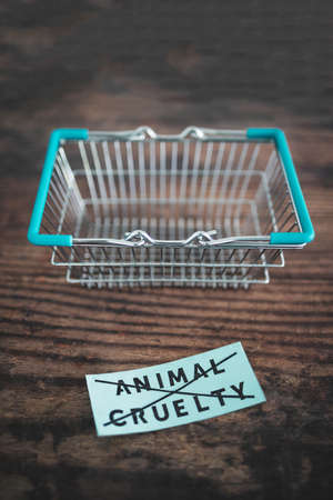 Crossed out animal cruelty product label with grocery shopping basket, concept of healthy nutrition and ethical choicesの写真素材
