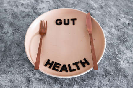 gut health text on dining plate with fork and knife, healthy nutrition and scientific research about the microbiomeの写真素材