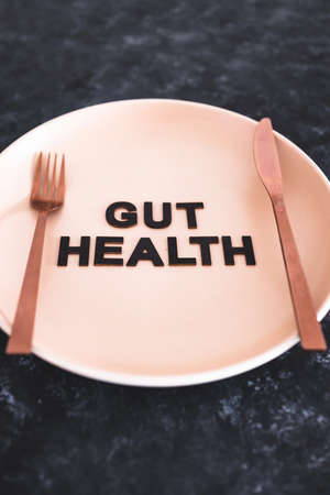gut health text on dining plate with fork and knife, healthy nutrition and scientific research about the microbiomeの写真素材