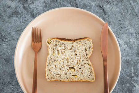 wholegrain multiseeds slice of bread on dining plate with fork and knife, concept of dieting vs healthy nutrition and intuitive eatingの写真素材