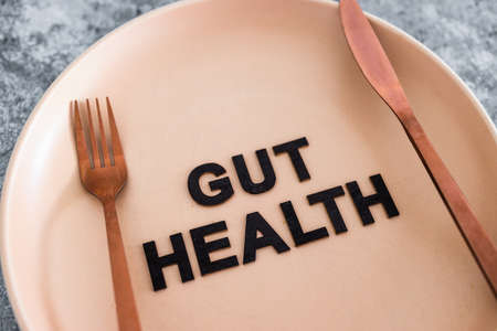 gut health text on dining plate with fork and knife, healthy nutrition and scientific research about the microbiomeの写真素材