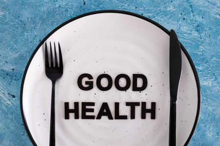 good health text on dining plate with fork and knife, concept of dieting vs healthy nutrition and intuitive eatingの写真素材