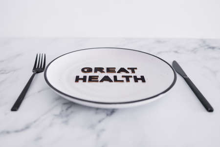 great health text on dining plate with fork and knife, concept of dieting vs healthy nutrition and intuitive eatingの写真素材