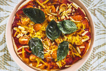 vegan margherita pizza with cherry tomatos and basil leaves topping, healthy plant-based food...