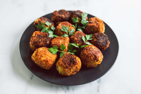 vegan pesto arancini fried risotto balls with fresh parsley as topping, healthy plant-based food...