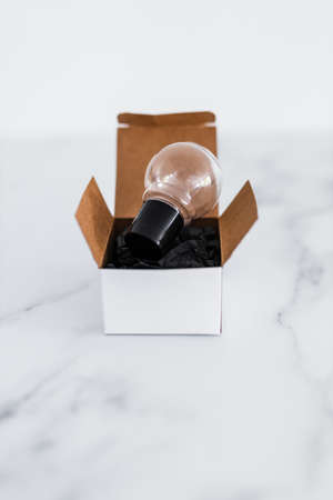 Think outside the box concept with idea lightbulb on top of white box on minimalist white marble...