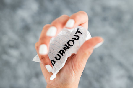 hand holding Burnout text on scrunched up piece of paper, psychology or mental health conceptの写真素材