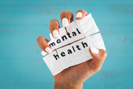 hand holding Mental health text on scrunched up piece of paper, psychology or stress and anxiety conceptの写真素材