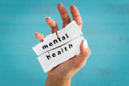 hand holding Mental health text on scrunched up piece of paper, psychology or stress and anxiety conceptの写真素材