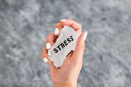 hand holding Stress text on scrunched up piece of paper, psychology or mental health conceptの写真素材