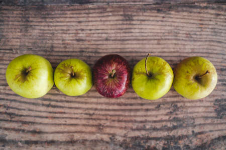 group of green apples with one red apple in the middle, concept of healthy food or metaphor of standing out from the crowdの写真素材