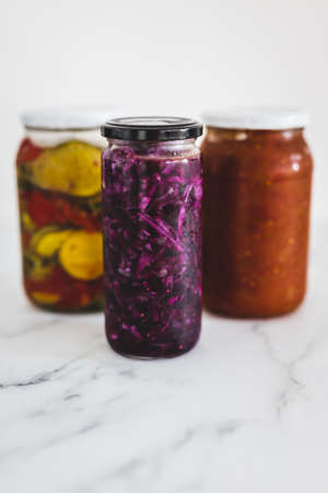 jars with homemade preserved sauerkraut vegetables and tomato chutney, concept of simple natural healthy ingredientsの写真素材