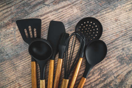 set of matching wooden and silicone kitchen utensils, concept of cooking meals at home or learning to cookの写真素材