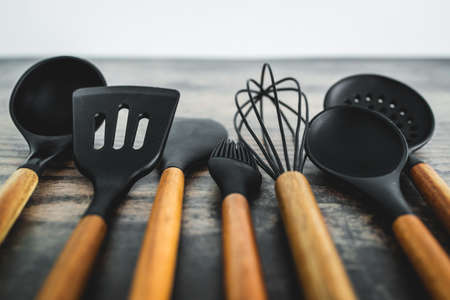 set of matching wooden and silicone kitchen utensils, concept of cooking meals at home or learning to cookの写真素材
