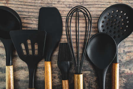 set of matching wooden and silicone kitchen utensils, concept of cooking meals at home or learning to cookの写真素材