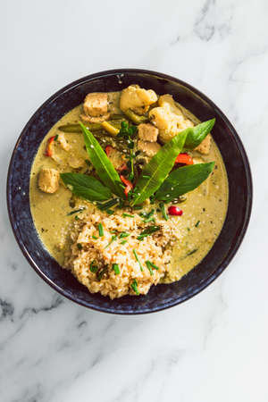 vegan green curry with tofu bell pepper and cauliflower served with brown rice, healthy plant-based food recipesの写真素材