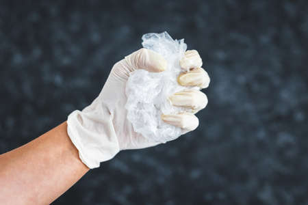 hand with glove picking up single-use plastic bag to be recycled, concept of cleaning the...