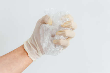 hand with glove picking up single-use plastic bag to be recycled, concept of cleaning the...