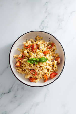 creamy vegan garlic fusilli pasta with cherry tomatoes and basil topping, healthy plant-based food recipesの写真素材