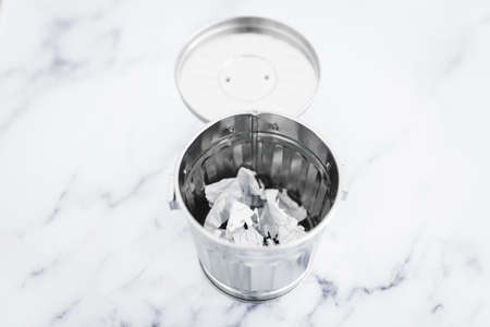 garbage bin with scrunched paper inside of it, concept of writer's block or changing your mind