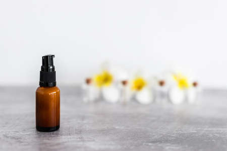 amber skincare bottle with flowers in the background, concept of natural beauty and organic ingredients in skincareの写真素材