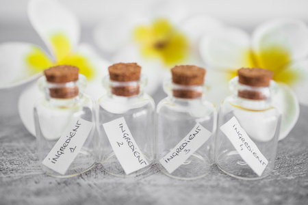 small bottles of ingredients with flowers in the background, concept of natural beauty and organic...