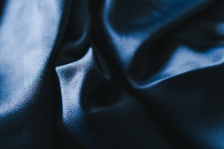 luxurious navy blue silk or satin fabric close-up for bedding or clothes, with soft wrinkle and light shining on itの写真素材