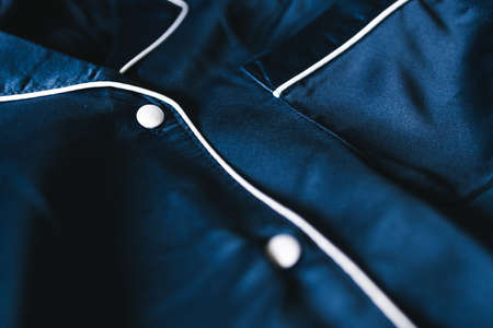 luxurious navy blue silk or satin tailored pyjama detail, fabric close-up with soft wrinkles and...