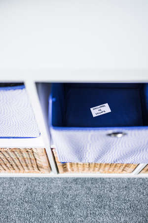 storage cube with Declutter of Dornate label inside of it with unfocused storage cabinet with other...