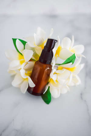 natural beauty and organic ingredients in skincare, apothecary skincare bottle with tropical frangipani flowers in the backgroundの写真素材