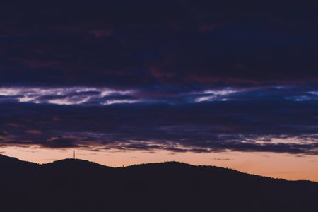 purple and orange sunset over the mountains with eucalyptus gum trees silhouettes shot in Tasmania in winterの写真素材