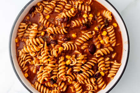vegan spiral pasta with spicy tomato sauce with beans and corn, healthy plant-based food recipes