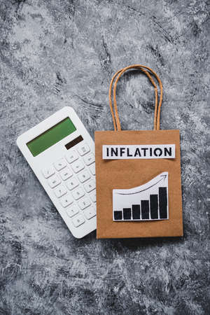 inflation and stagnating economy conceptual image with text over shopping bag with graphs showing...