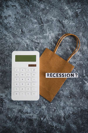 recession and stagnating economy conceptual image with text over shopping bag next to calculatorの写真素材