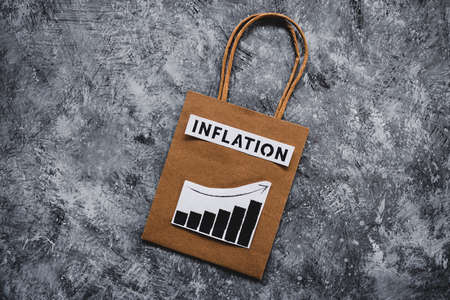 inflation and stagnating economy conceptual image with text over shopping bag with graphs showing...